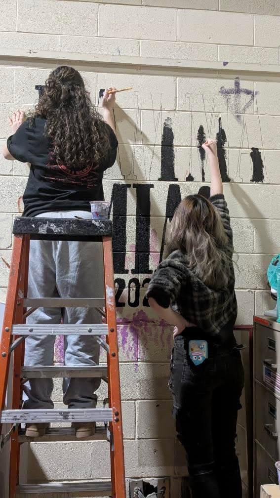 From left: Brianna Lopes-Amorim and Sophia Xu painting the mural for JFK's production of Mamma Mia. Every senior that was associated with the production was able to put a hand print on the mural.